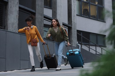 Photo of Being late. Worried women with suitcases running outdoors