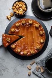 Photo of Sliced delicious caramel cheesecake with popcorn served on light grey table, flat lay