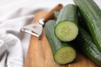 Many fresh cucumbers on wooden board, closeup. Space for text