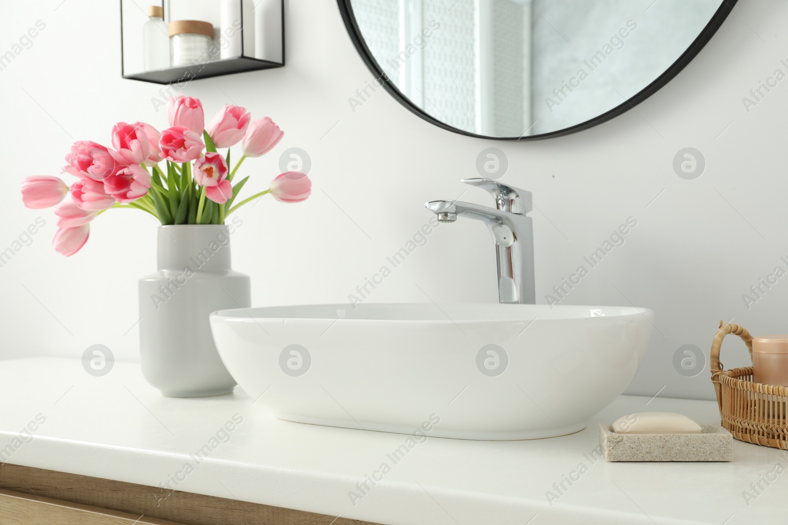 Photo of Vase with beautiful pink tulips near sink in bathroom