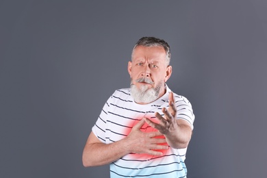 Photo of Mature man having heart attack on gray background