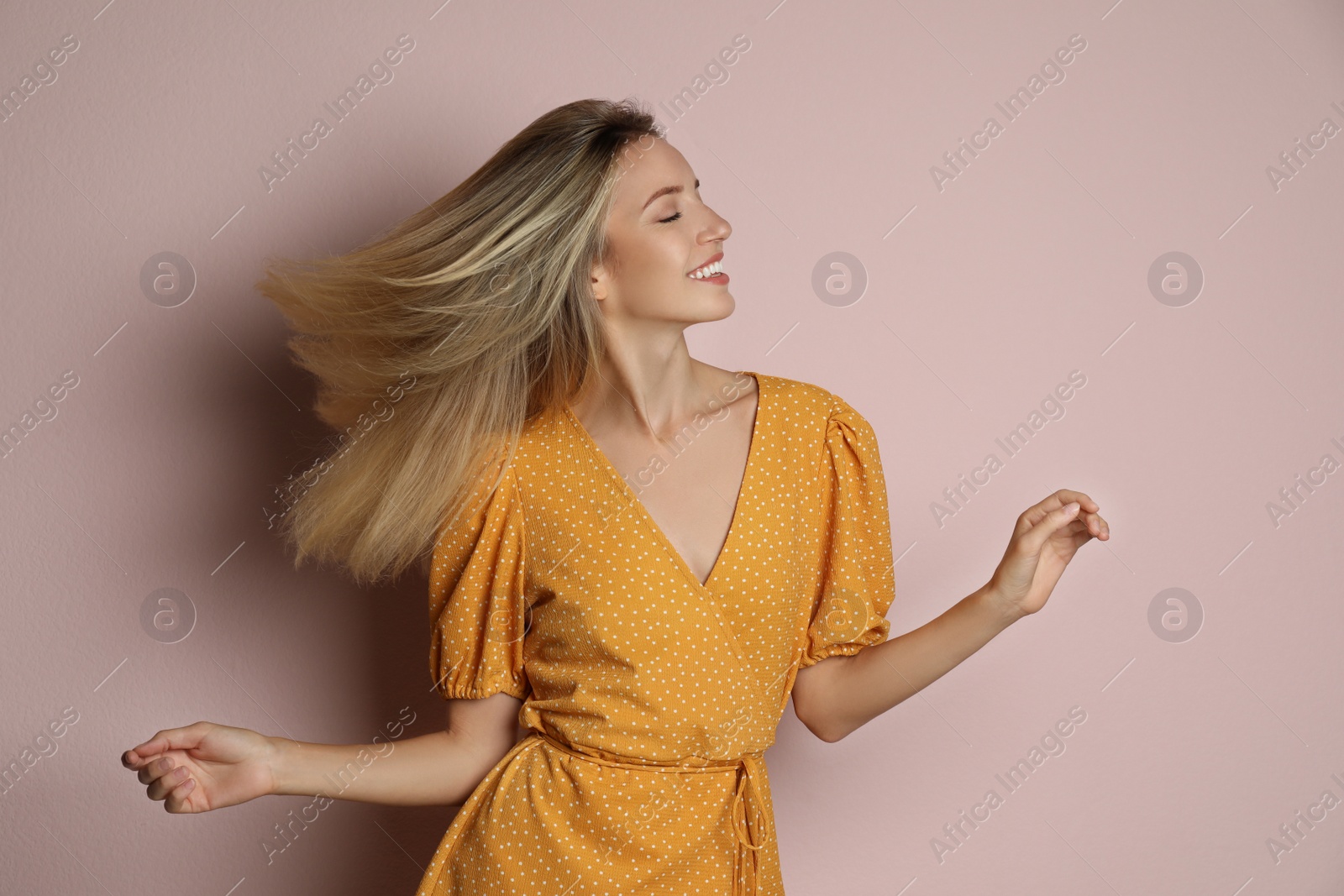 Photo of Young woman wearing stylish dress on pale pink background