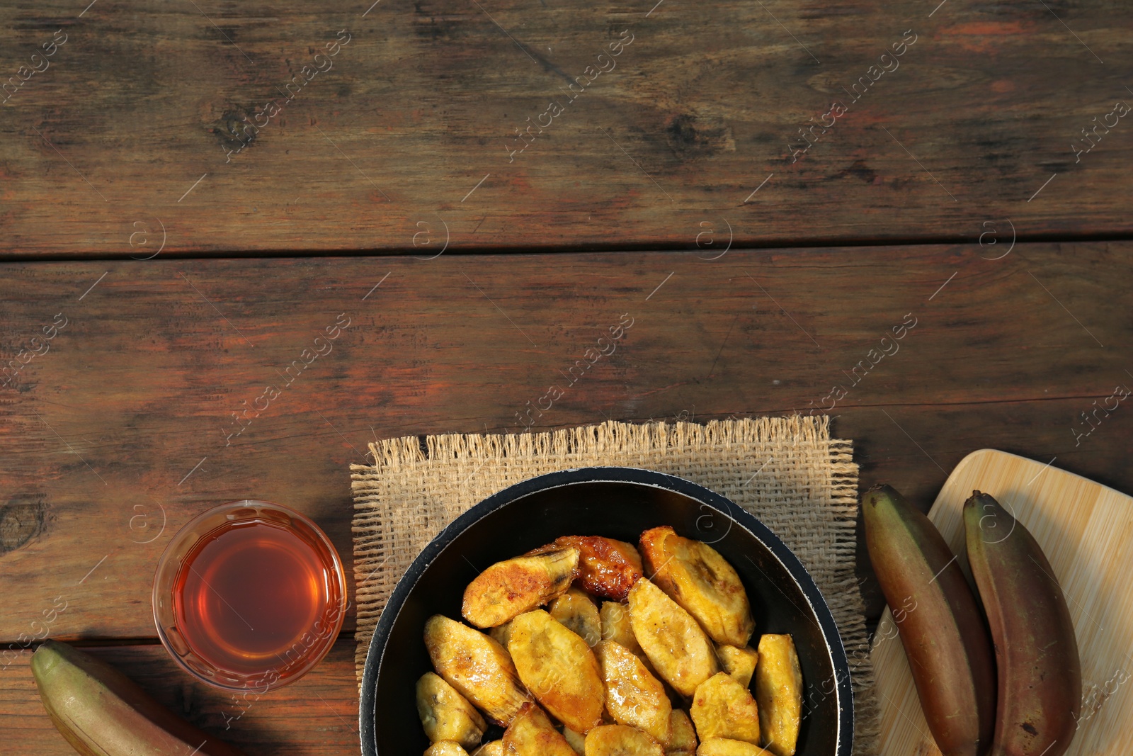 Photo of Flat lay composition with deep fried banana slices on wooden table. Space for text