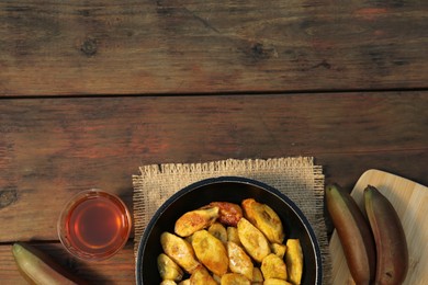 Flat lay composition with deep fried banana slices on wooden table. Space for text