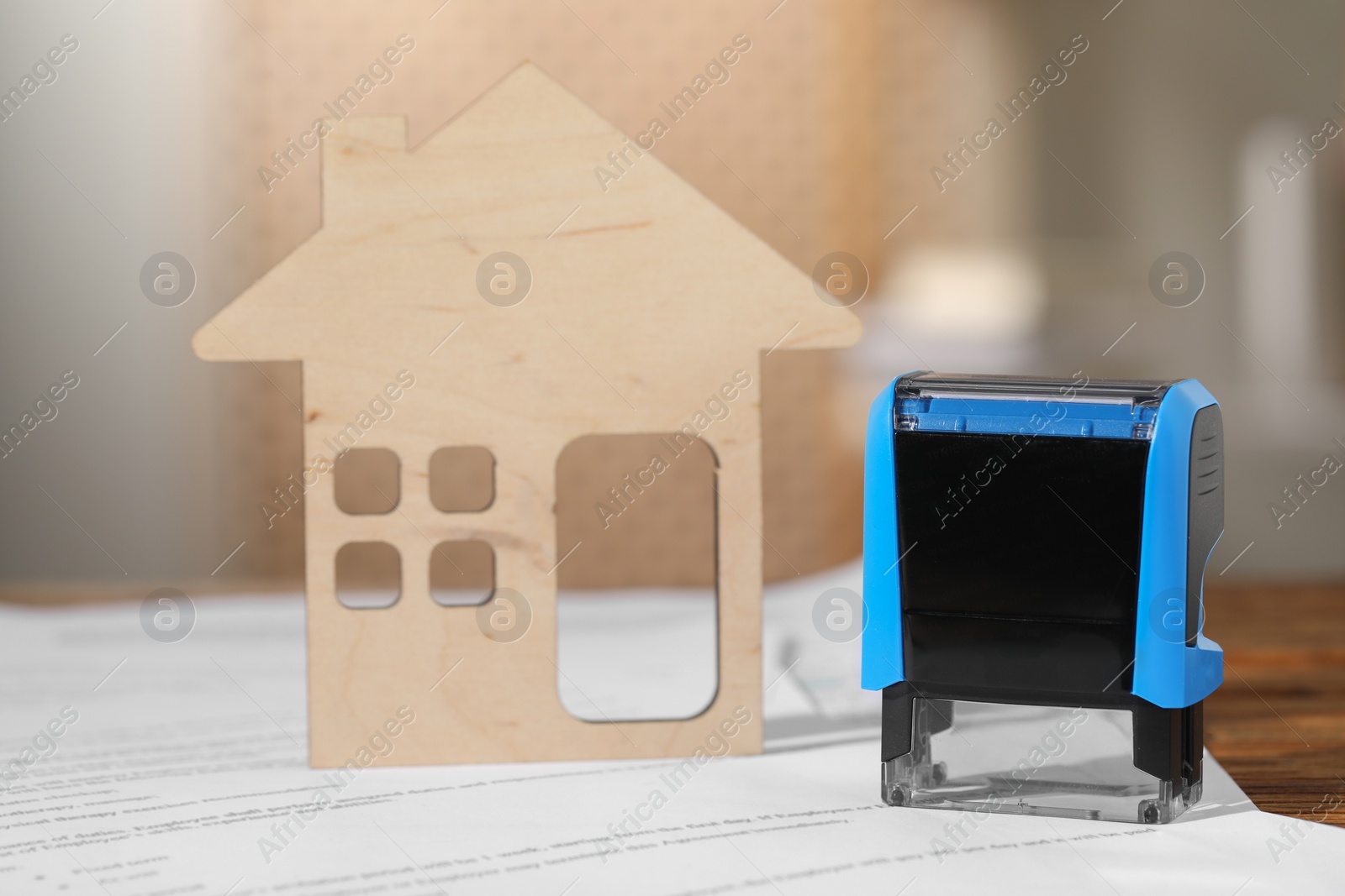 Photo of Notary contract. Stamp, figure of house and document on table, closeup