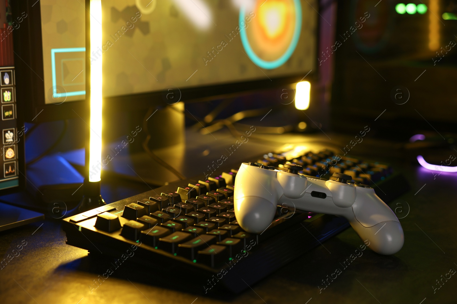 Photo of Playing video games. Computer keyboard and wireless controller on table indoors