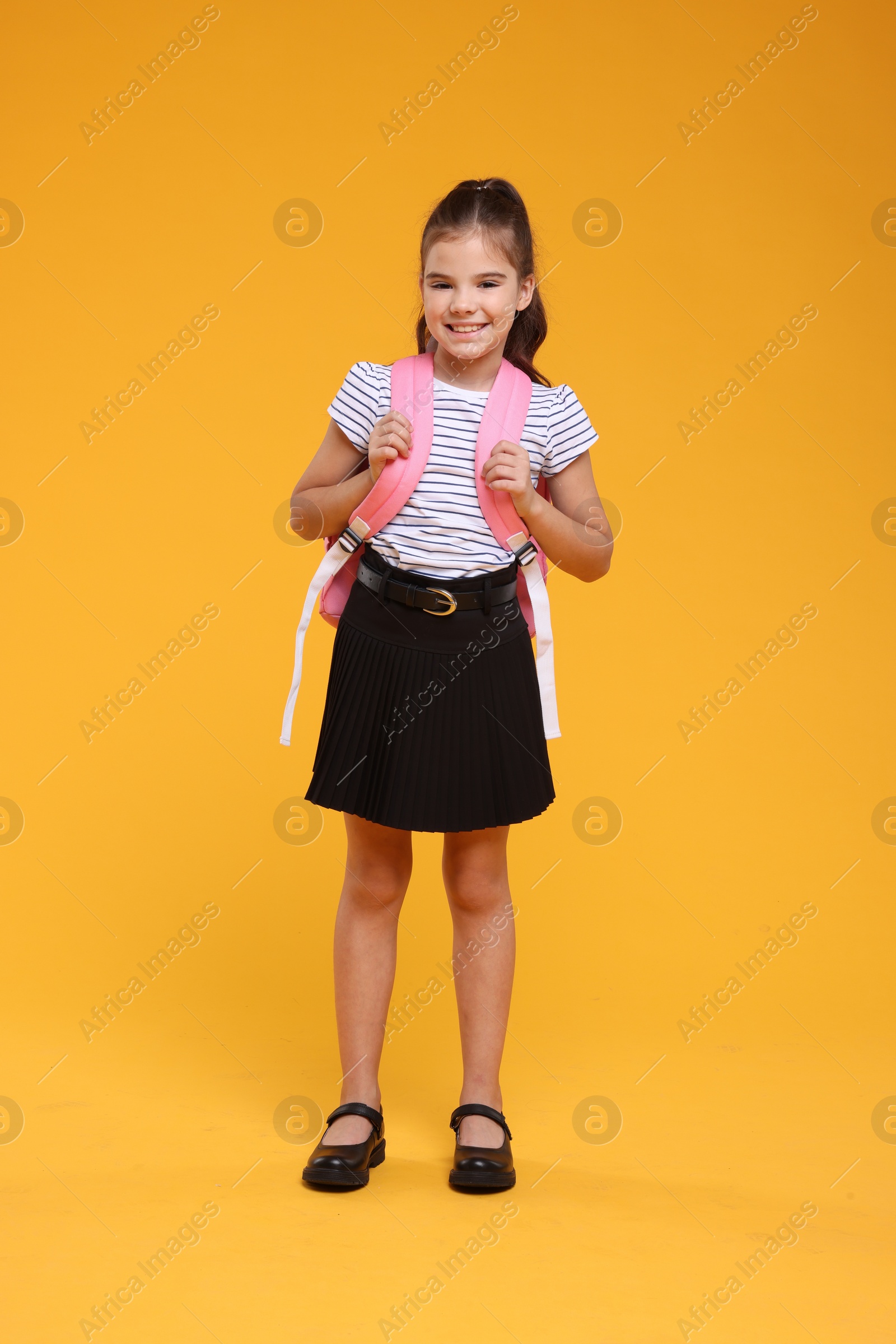 Photo of Back to school. Cute girl with backpack on orange background