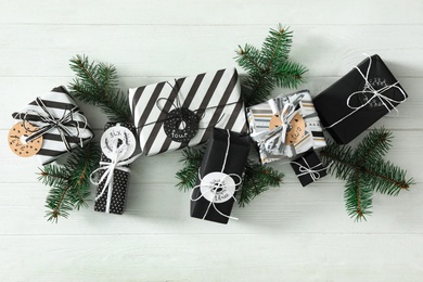 Photo of Gifts for Christmas advent calendar and fir branches on white wooden table, flat lay.