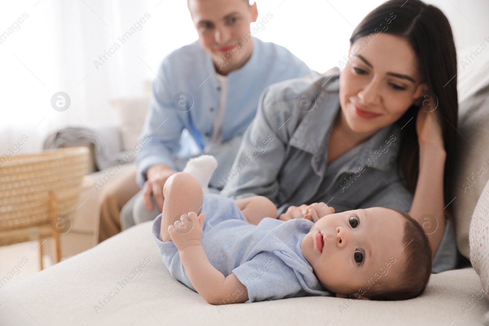 Photo of Happy family with cute baby on sofa at home, space for text