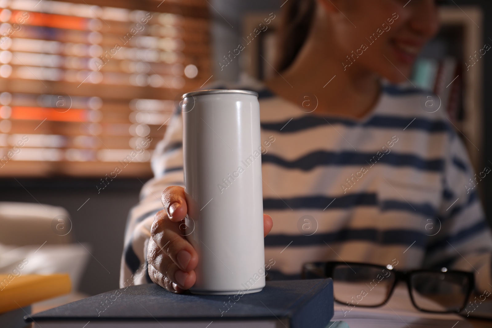 Photo of Young woman with energy drink studying at home, closeup