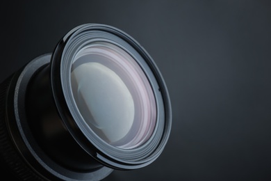 Photo of Lens of professional camera on black background, closeup. Space for text