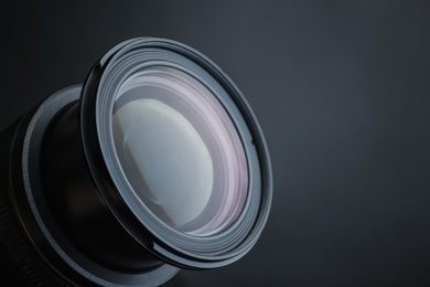 Lens of professional camera on black background, closeup. Space for text