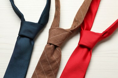 Photo of Different neckties on white wooden table, flat lay