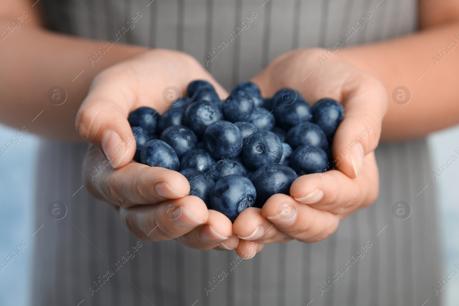 Photo of Young woman holding tasty ripe blueberries, closeup