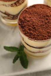 Photo of Delicious tiramisu in glasses and mint on table, above view