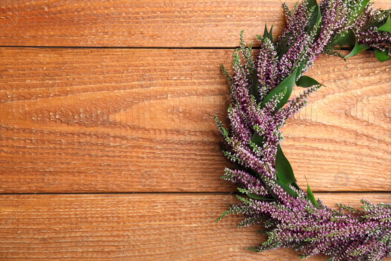 Photo of Beautiful autumnal wreath with heather flowers on wooden background, top view. Space for text