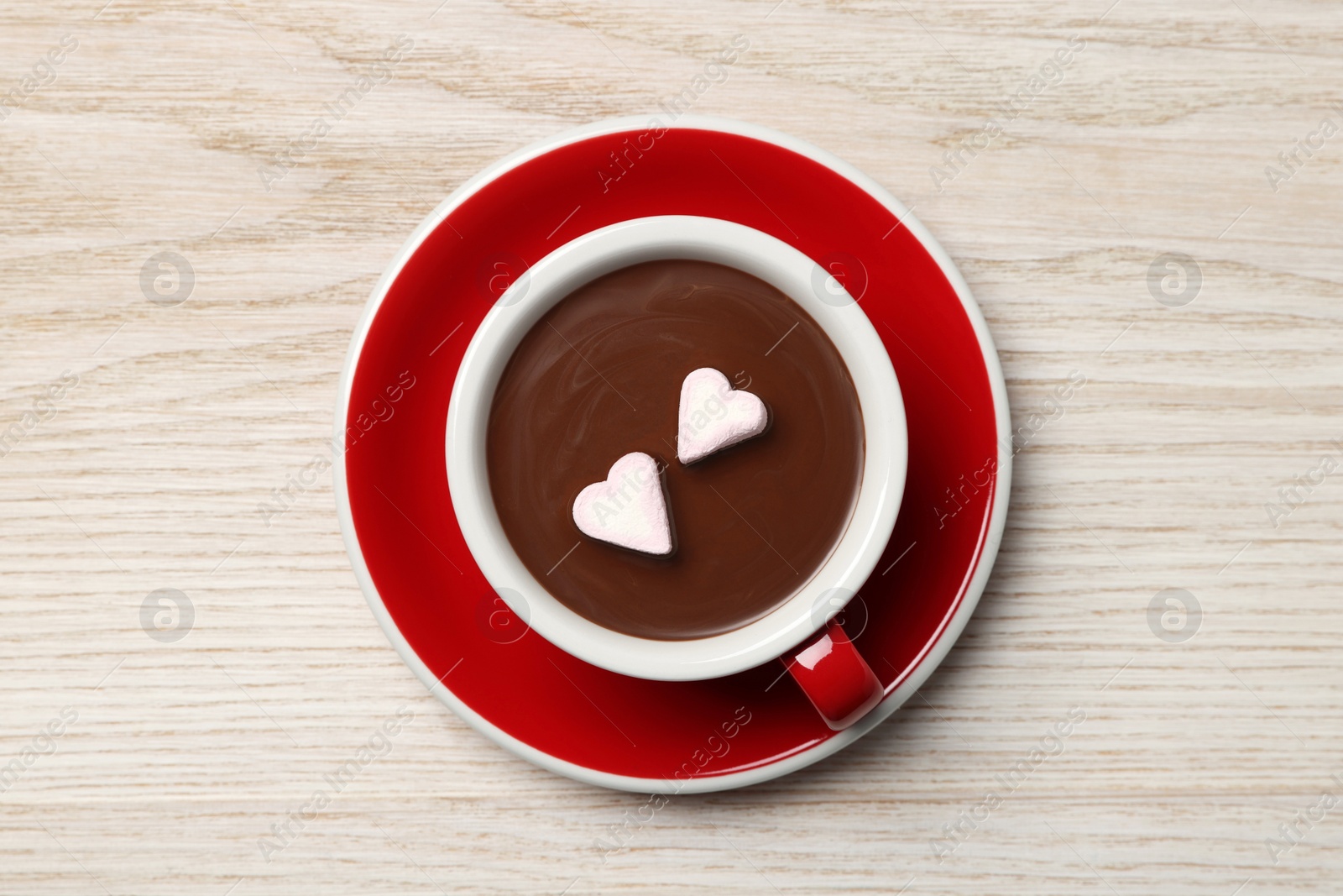 Photo of Cup of hot chocolate with heart shaped marshmallows on white wooden table, top view