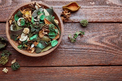 Photo of Aromatic potpourri of dried flowers in bowl on wooden table, flat lay. Space for text