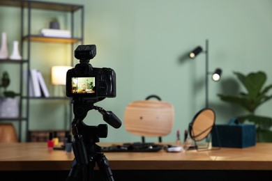 Beauty blogger's workplace. Cosmetic products on table indoors, focus on camera