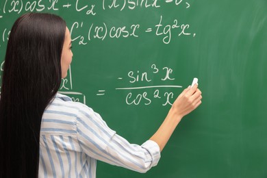 Photo of Young teacher explaining mathematics at chalkboard in classroom