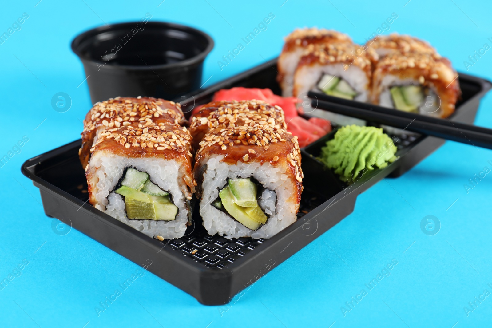 Photo of Box with sushi rolls on color background. Food delivery