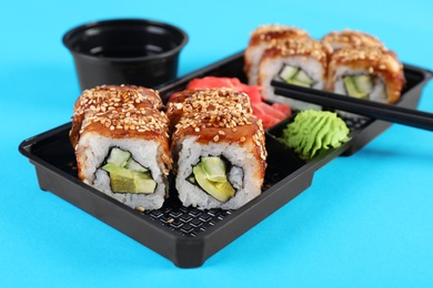 Box with sushi rolls on color background. Food delivery