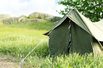 Photo of Camping tent in green field on sunny day. Space for text