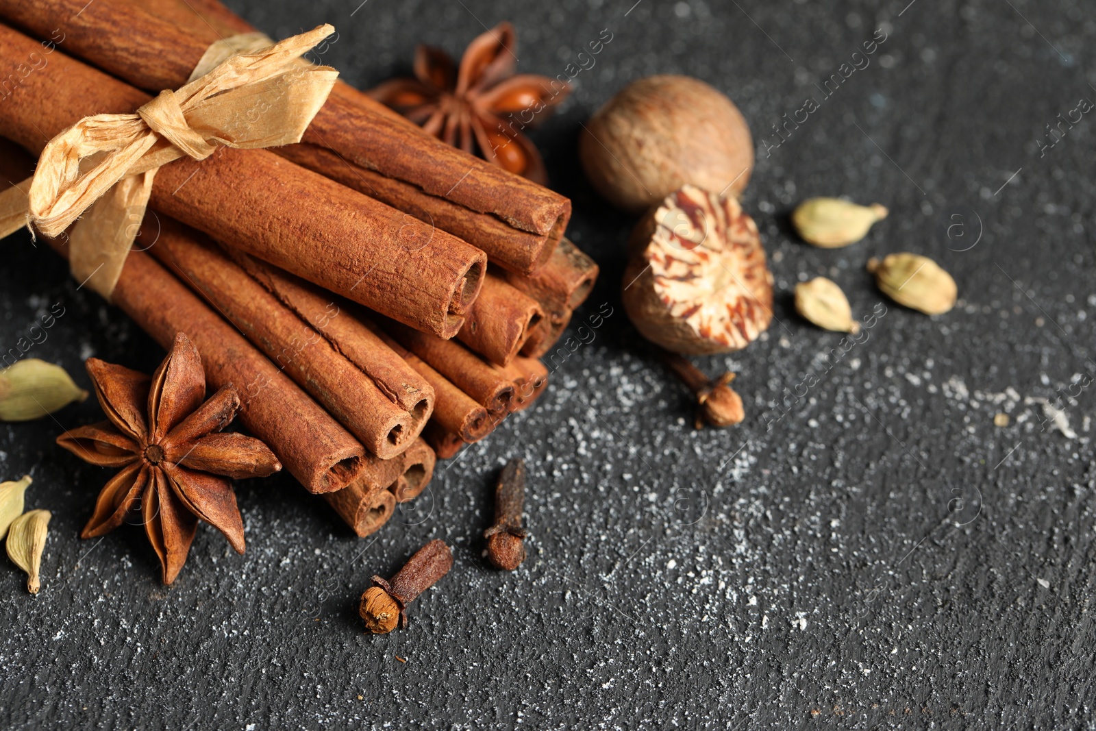 Photo of Different aromatic spices on grey textured table, closeup. Space for text