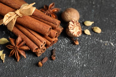 Photo of Different aromatic spices on grey textured table, closeup. Space for text