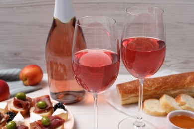 Delicious rose wine and snacks on white table, closeup