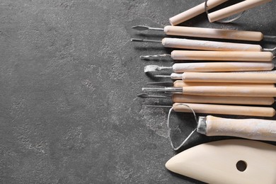 Photo of Set of different clay crafting tools on grey table, top view. Space for text