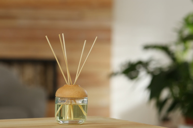 Photo of Aromatic reed air freshener on table indoors. Space for text