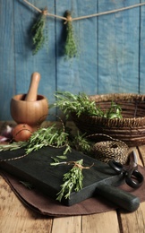 Photo of Wooden board with rosemary on table. Aromatic herbs