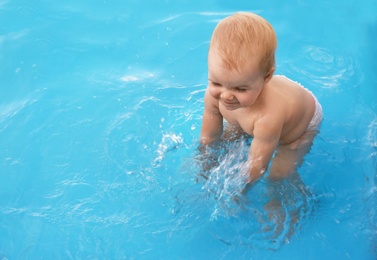 Photo of Little baby playing in outdoor swimming pool. Dangerous situation