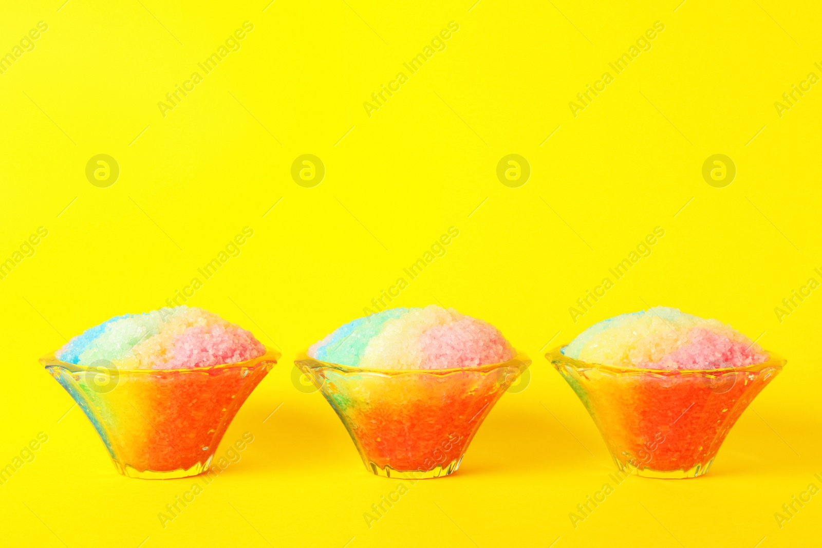 Photo of Rainbow shaving ice in glass dessert bowls on yellow background