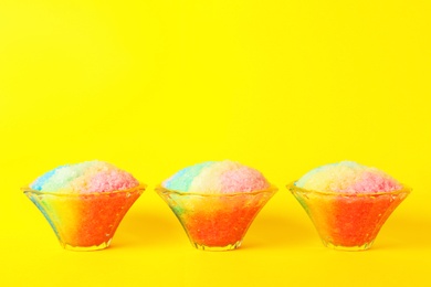 Rainbow shaving ice in glass dessert bowls on yellow background