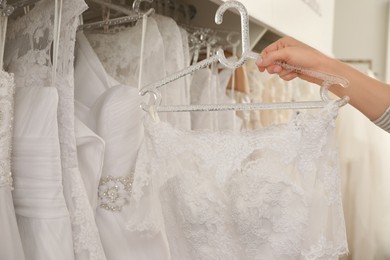 Photo of Young woman choosing wedding dress in salon, closeup