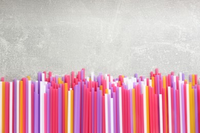 Colorful plastic drinking straws on grey stone table, flat lay. Space for text