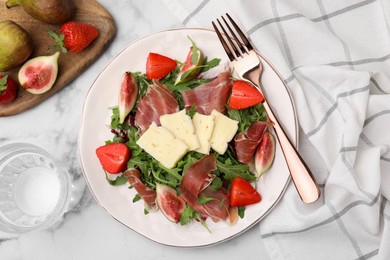 Tasty salad with brie cheese, prosciutto, strawberries and figs served on white marble table, flat lay