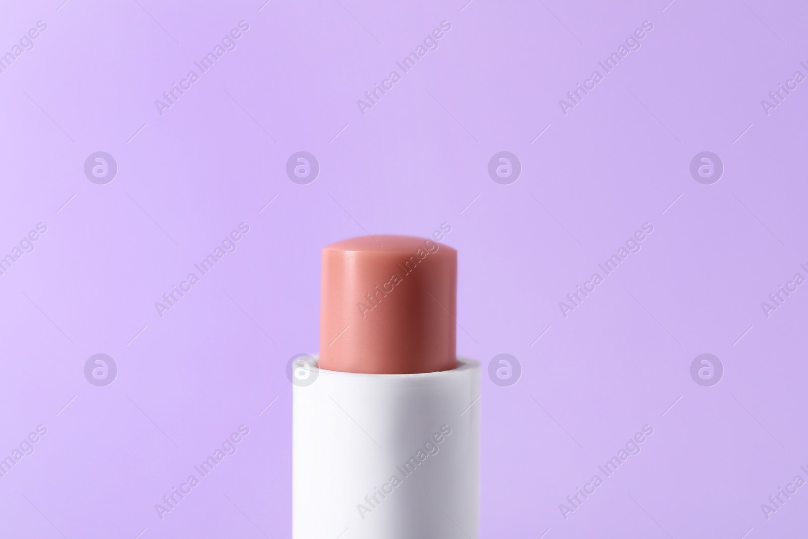 Photo of One lip balm on lilac background, closeup. Cosmetic product