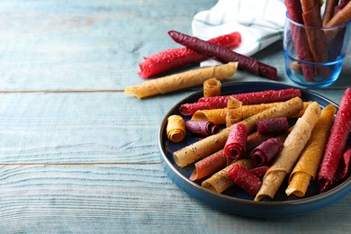 Delicious fruit leather rolls on blue wooden table. Space for text