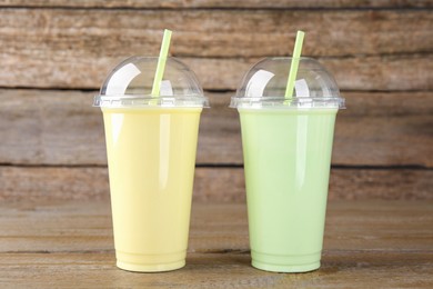 Plastic cups with different tasty smoothies on wooden table