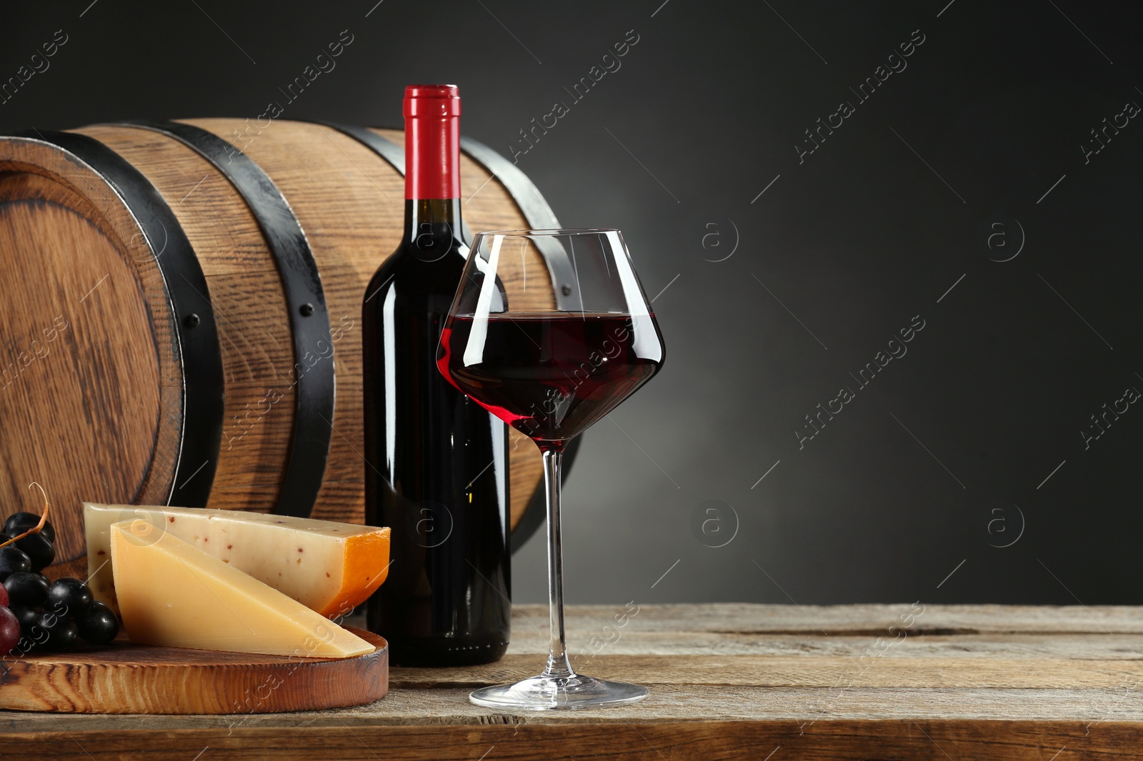 Photo of Winemaking. Composition with tasty wine and barrel on wooden table against dark background, space for text
