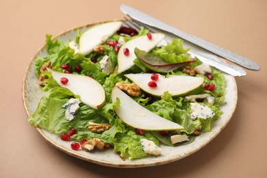 Photo of Delicious pear salad and cutlery on beige background, closeup