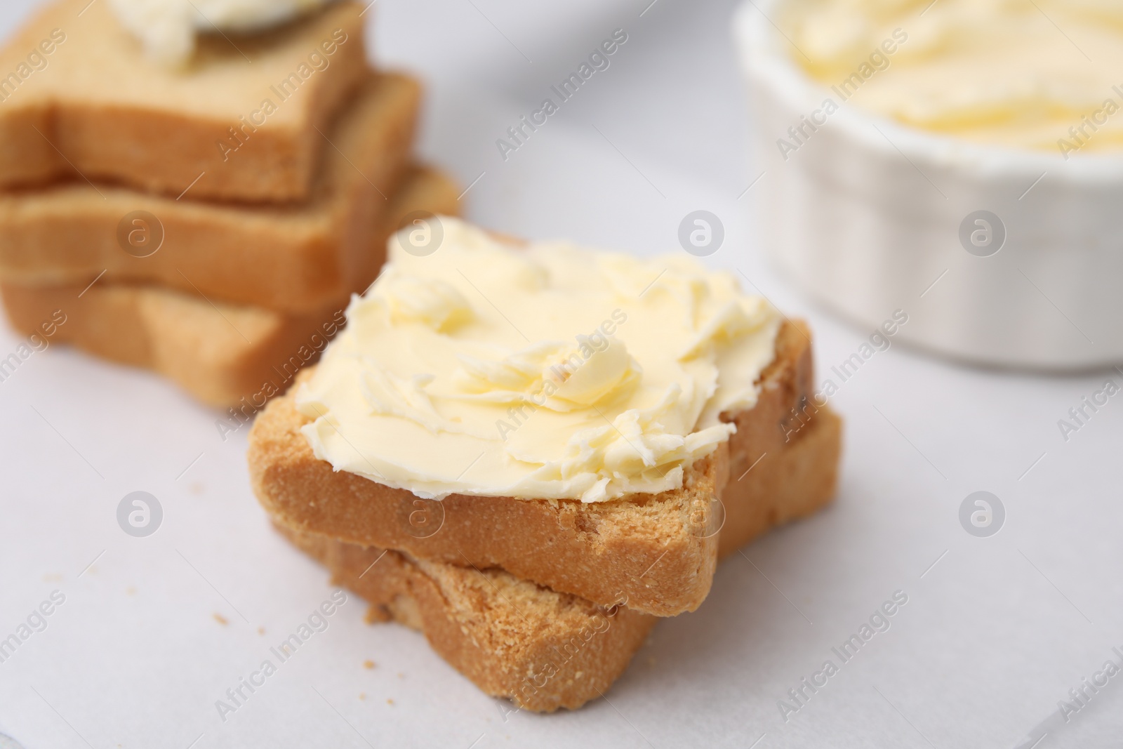 Photo of Slices of bread with tasty butter on light table, closeup