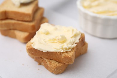 Slices of bread with tasty butter on light table, closeup