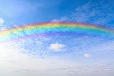 Beautiful rainbow in blue sky with white clouds on sunny day