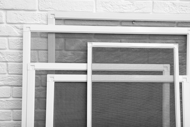 Photo of Set of window screens near white brick wall, closeup