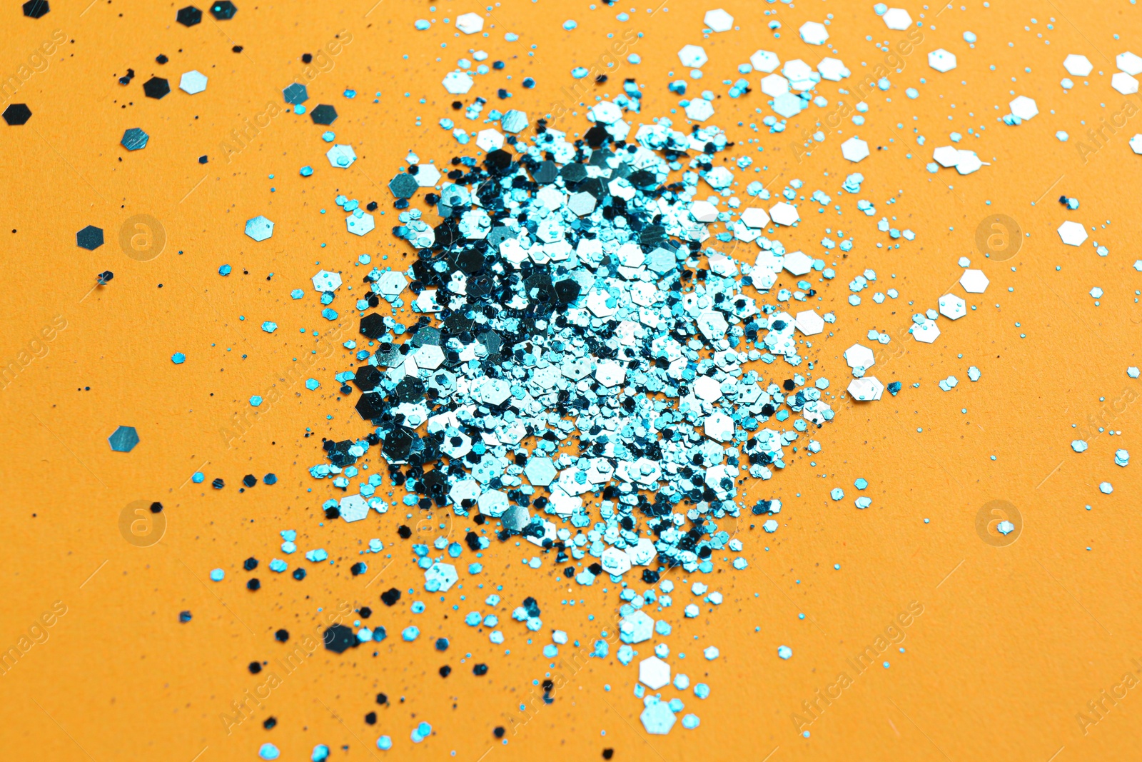 Photo of Shiny bright light blue glitter on orange background