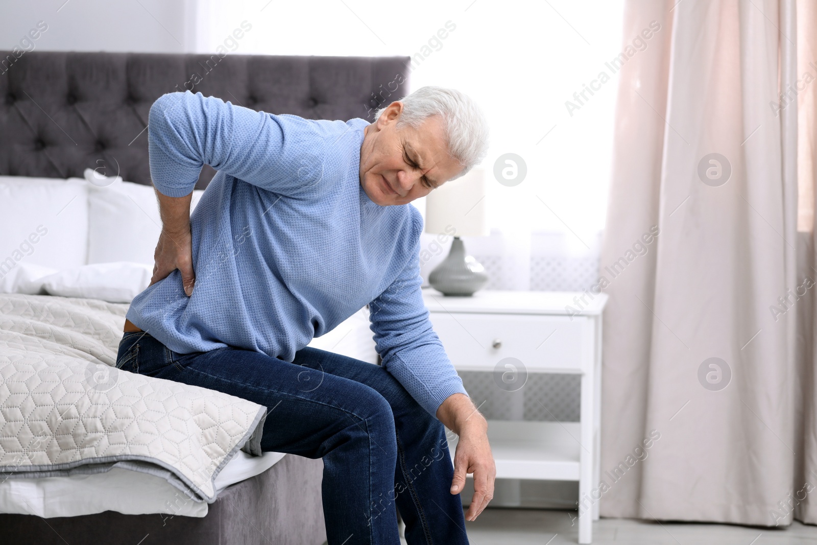 Photo of Senior man suffering from back pain at home